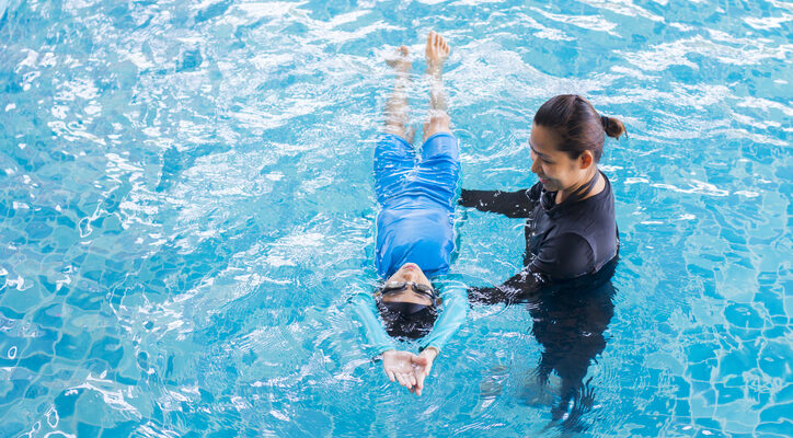 Girl learning to swim with coach at the leisure center