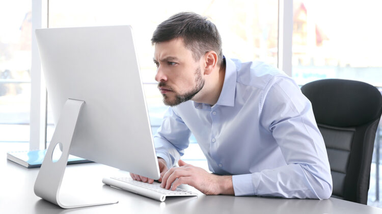 A man sitting on a computer with a poor posture