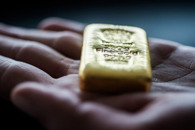 Person holding a gold bullion on a palm of the hand.
