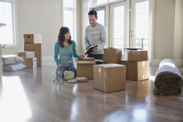 Couple unpacking cardboard boxes in new home